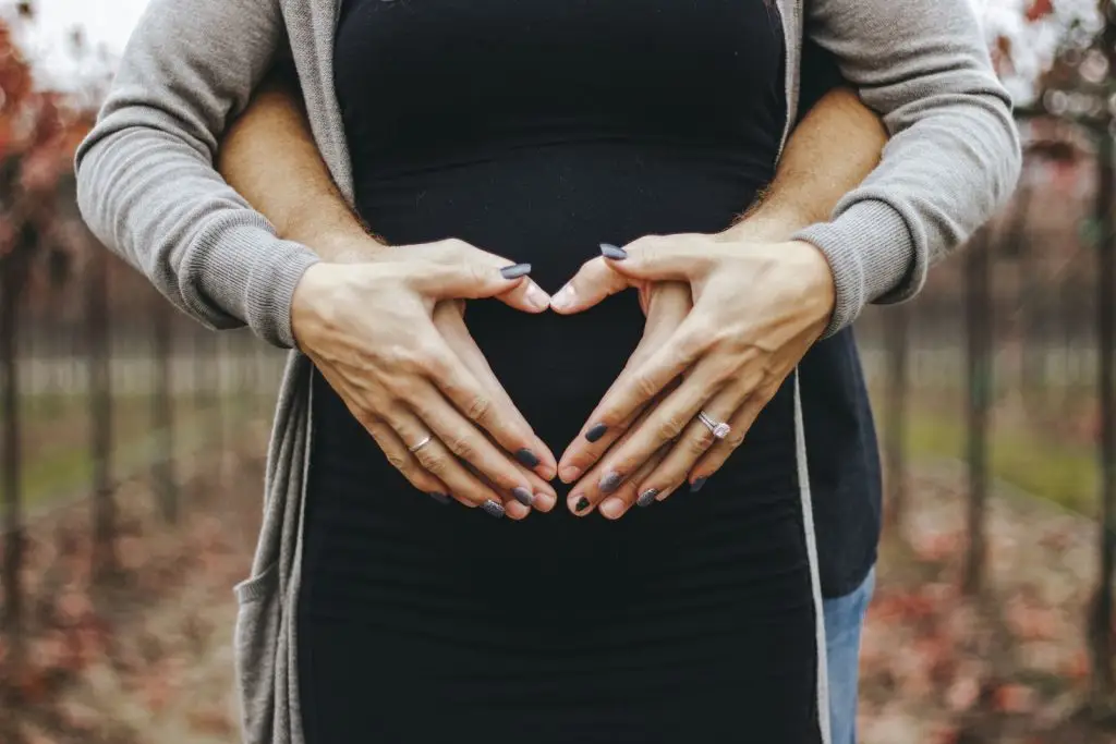 heart hands over pregnant stomach
